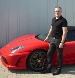 Ingo Laging vor einem roten Ferrari vor der Werkstatt
