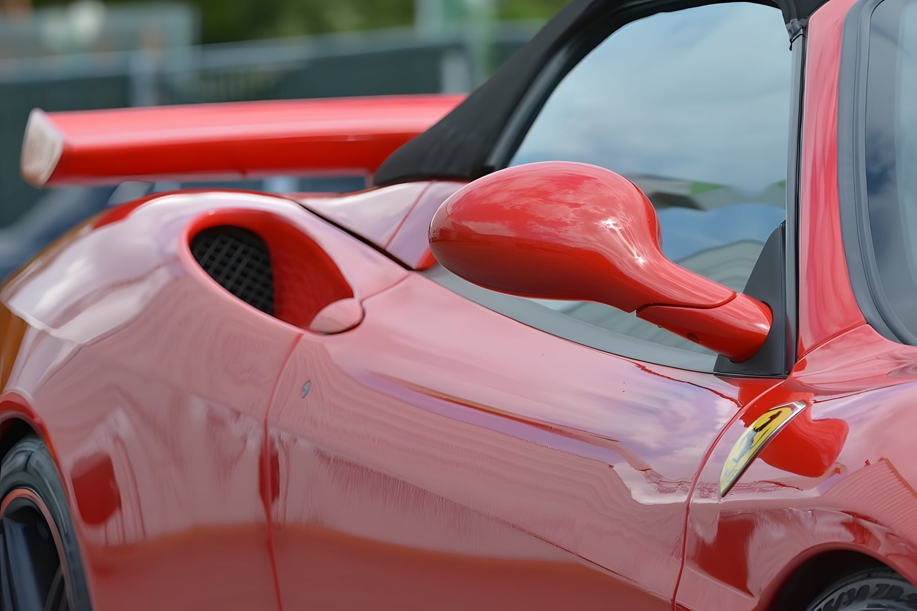 Seitenansicht eines roten Ferrari mit Lufteinlass und Spiegel